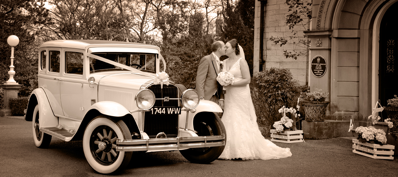 bride and groom kissing at side of wedding car